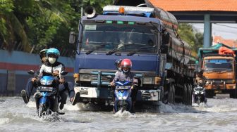 Seorang pengendara motor mendorong kendaraannya melintasi banjir rob di Jalan Kalimas Baru, Surabaya, Jawa Timur, Rabu (18/5/2022).  ANTARA FOTO/Didik Suhartono
