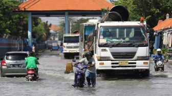 Seorang pengendara motor mendorong kendaraannya melintasi banjir rob di Jalan Kalimas Baru, Surabaya, Jawa Timur, Rabu (18/5/2022).  ANTARA FOTO/Didik Suhartono
