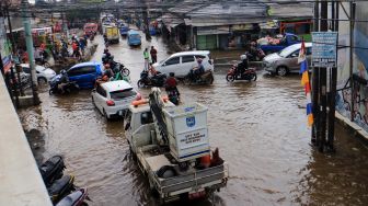 Sejumlah pengendara kendaraan menerobos genangan banjir di Jalan Raya Sawangan, Perempatan Mampang, Depok, Jawa Barat, Rabu (18/5/2022).  ANTARA FOTO/Yulius Satria Wijaya