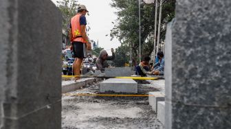 Pekerja menyelesaikan proyek revitalisasi jalur pedestrian di kawasan Kota Tua, Jakarta Barat, Kamis (19/5/2022). [Suara.com/Alfian Winanto]