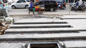 Pekerja menyelesaikan proyek revitalisasi jalur pedestrian di kawasan Kota Tua, Jakarta Barat, Kamis (19/5/2022). [Suara.com/Alfian Winanto]