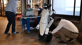 Teknisi memeriksa robot humanoid R1 ketika istirahat di museum Palazzo Madama, Turin, Italia, Kamis (12/5/2022). [MARCO BERTORELLO / AFP]
