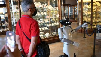 Robot humanoid R1 saat memandu Pengunjung di ruang keramik museum Palazzo Madama, Turin, Italia, Kamis (12/5/2022). [MARCO BERTORELLO / AFP]
