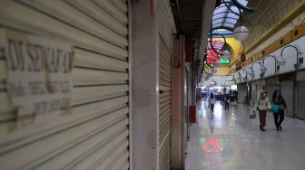 Warga melintasi deretan kios yang tutup di Mal Blok M, Jakarta, Minggu (22/5/2022). [Suara.com/Angga Budhiyanto]