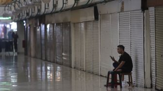 Seorang pedagang menunggu pembeli di depan deretan kios yang tutup di Mal Blok M, Jakarta, Minggu (22/5/2022). [Suara.com/Angga Budhiyanto]