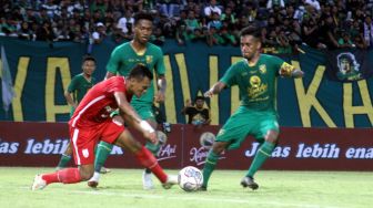 Striker Persis Solo, Ferdinand Sinaga berusaha melewati dua pemain Persebaya Surabaya di Stadion Gelora Bung Tomo, Minggu (22/5/2022). [Suara.com/Ronald Seger Prabowo]