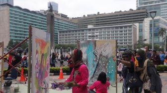 Seniman yang tergabung dalam Perempuan Perupa Indonesia melukis dan menggelar pameran bersama di depan Pos Polisi Thamrin, Jakarta, Minggu (22/5/2022). [Suara.com/Angga Budhiyanto]