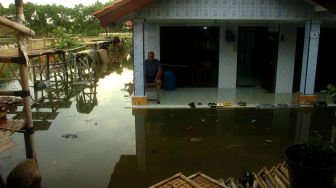 Seorang warga duduk di depan rumahnya yang terendam banjir rob (banjir pasang air laut) di Kelurahan Muarareja, Tegal, Jawa Tengah, Senin (23/5/2022). ANTARA FOTO/Oky Lukmansyah