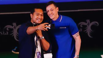 Pesepakbola Mesut Ozil berswafoto dengan fans dalam konferensi pers di Kementerian Pariwisata, Ekonomi dan Kreatif (Kemenparekraf), Jakarta Pusat, Rabu (25/5/2022). [Suara.com/Alfian Winanto]