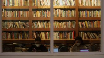 Pengunjung membaca buku di perpustakaan &quot;Baca Di Tebet&quot;, Jakarta, Rabu (25/5/2022). [Suara.com/Angga Budhiyanto]