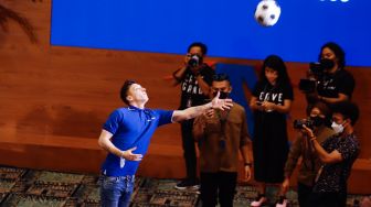 Pesepakbola Mesut Ozil melempar bola yang sudah ditandatangani untuk fans saat konferensi pers di Kementerian Pariwisata, Ekonomi dan Kreatif (Kemenparekraf), Jakarta Pusat, Rabu (25/5/2022). [Suara.com/Alfian Winanto]