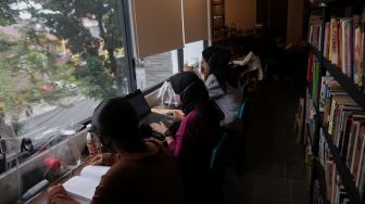 Pengunjung membaca buku di perpustakaan &quot;Baca Di Tebet&quot;, Jakarta, Rabu (25/5/2022). [Suara.com/Angga Budhiyanto]