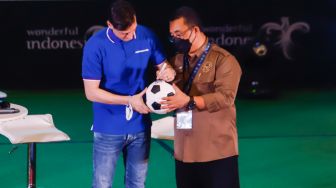 Pesepakbola Mesut Ozil menandatangani bola untuk fans dalam konferensi pers di Kementerian Pariwisata, Ekonomi dan Kreatif (Kemenparekraf), Jakarta Pusat, Rabu (25/5/2022). [Suara.com/Alfian Winanto]