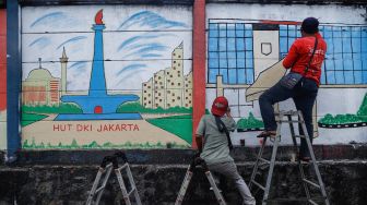 Petugas PPSU membuat mural pada tembok di Jalan R.E Martadinata, Tanjung Priok, Jakarta Utara, Rabu (25/5/2022). [Suara.com/Alfian Winanto]
