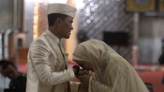 Artis Juliana Moechtar meencium tangan suaminya, Letkol Inf Nur Wahyudi saat akad nikah di Masjid Istiqlal, Jakarta, Jumat (27/5/2022). [Suara.com/Angga Budhiyanto]