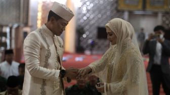 Mempelai pria Letkol Inf Nur Wahyudi memasangkan cincin kepada istrinya, Juliana Moechtar saat akad nikah di Masjid Istiqlal, Jakarta, Jumat (27/5/2022). [Suara.com/Angga Budhiyanto]