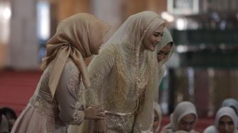 Artis Juliana Moechtar (kanan) bersiap untuk menandatangani buku nikah saat akad nikah di Masjid Istiqlal, Jakarta, Jumat (27/5/2022). [Suara.com/Angga Budhiyanto]