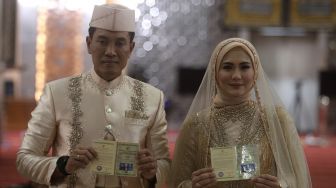 Pasangan Juliana Moechtar dan Letkol Inf Nur Wahyudi menunjukkan buku nikah saat akad nikah di Masjid Istiqlal, Jakarta, Jumat (27/5/2022). [Suara.com/Angga Budhiyanto]