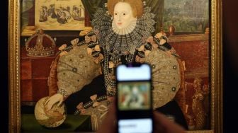 Seorang karyawan Sotheby menggunakan teleponnya untuk mengambil foto 'The Armada Portrait of Elizabeth I' yang dilukis pada tahun 1588 saat sesi pemotretan untuk mempromosikan Sotheby's Jubilee Season, saat sesi pemotretan untuk mempromosikan Sotheby's Jubilee Season, di London, Inggris, Jumat (27/5/2022). [ADRIAN DENNIS / AFP]