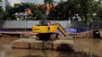 Alat berat yang digunakan untuk menyelesaikan pembangunan turap anakKali Ciliwung terparkir di kawasan Pasar Baru, Jakarta, Minggu (29/5/2022). [Suara.com/Angga Budhiyanto]