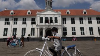 Warga menaiki sepeda saat berwisata di Taman Fatahillah, Kota Tua, Jakarta, Minggu (29/5/2022). [Suara.com/Angga Budhiyanto]