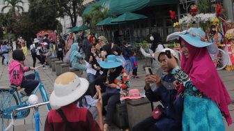 Warga berwisata di Taman Fatahillah, Kota Tua, Jakarta, Minggu (29/5/2022). [Suara.com/Angga Budhiyanto]