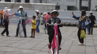 Warga menaiki sepeda saat berwisata di Taman Fatahillah, Kota Tua, Jakarta, Minggu (29/5/2022). [Suara.com/Angga Budhiyanto]