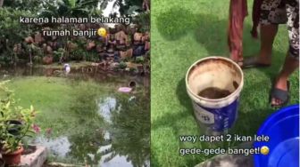 Halaman Rumah Banjir, Bapak-Bapak Ini Malah Iseng Mancing Ikan Lele