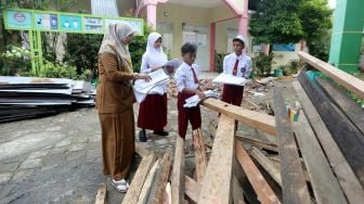 Pengajar dan pelajar Sekolah Dasar Negeri (SDN) 48 membenahi berkas dan alat dari ruangan guru yang atapnya rusak akibat bencana angin kencang di Banda Aceh, Aceh, Senin (30/5/2022).  ANTARA FOTO / Irwansyah Putra
