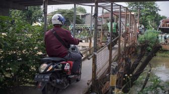 Pengendara motor melintasi Jembatan Penyebrangan Orang (JPO) di atas sungai Kalimalang di Jl. KH. Noer Ali, Kalimalang, Jakarta Timur, Kamis (2/6/2022). [Suara.com/Alfian Winanto]