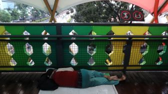 Warga tertidur di jembatan penyeberangan orang (JPO) di kawasan Pasar Minggu, Jakarta, Kamis (2/6/2022). [Suara.com/Angga Budhiyanto]