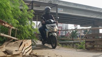 Pengendara motor melintasi Jembatan Penyebrangan Orang (JPO) di atas sungai Kalimalang di Jl. KH. Noer Ali, Kalimalang, Jakarta Timur, Kamis (2/6/2022). [Suara.com/Alfian Winanto]