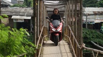 Pengendara motor melintasi Jembatan Penyebrangan Orang (JPO) di atas sungai Kalimalang di Jl. KH. Noer Ali, Kalimalang, Jakarta Timur, Kamis (2/6/2022). [Suara.com/Alfian Winanto]