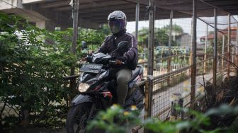 Pengendara motor melintasi Jembatan Penyebrangan Orang (JPO) di atas sungai Kalimalang di Jl. KH. Noer Ali, Kalimalang, Jakarta Timur, Kamis (2/6/2022). [Suara.com/Alfian Winanto]