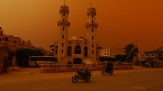 Pengendara motor melewati sebuah masjid saat badai pasir melanda di pinggiran kota Dana, provinsi Idlib, Suriah, Kamis (2/6/2022). [aaref watad /AFP]