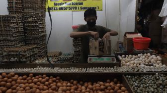 Pedagang mengemas telur ayam pesanan pembeli di salah satu kios di Pasar Minggu, Jakarta, Minggu (5/6/2022). [Suara.com/Angga Budhiyanto]