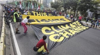 Sejumlah aktivis Greenpeace dan Bike2Work membentangkan spanduk saat aksi memperingati Hari Lingkungan Hidup Sedunia di Jalan Sudirman, Jakarta, Minggu (5/6/2022).  ANTARA FOTO/Asprilla Dwi Adha