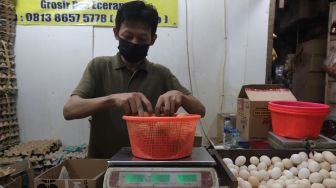 Pedagang menimbang telur ayam pesanan pembeli di salah satu kios di Pasar Minggu, Jakarta, Minggu (5/6/2022). [Suara.com/Angga Budhiyanto]