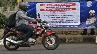 Pengendara melintas di dekat spanduk sosialisasi pemberlakuan aturan ganjil genap di Jalan Gajah Mada, Jakarta, Senin (6/6/2022). ANTARA FOTO/Aditya Pradana Putra