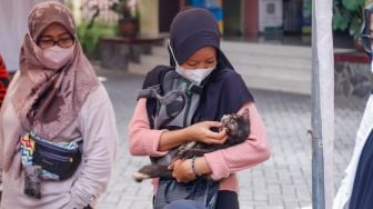 Warga membawa hewan peliharaannya untuk divaksin rabies di Kantor Kecamatan Duren Sawit, Jakarta Timur, Selasa (7/6/2022). [Suara.com/Alfian Winanto]