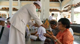 Pemuka agama Hindu memercikkan air suci kepada umat saat sembahyang Hari Raya Galungan di Pura Jagadnata, Banguntapan, Bantul, DI Yogyakarta, Rabu (8/6/2022). [ANTARA FOTO/Fikri Yusuf/rwa]