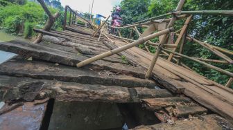 Warga melintasi akses jembatan yang rusak penghubung antara kecamatan Jonggol dan kecamatan Klapanunggal di Singasari, Jonggol, Kabupaten Bogor, Jawa Barat, Selasa (7/6/2022). [ANTARA FOTO/Yulius Satria Wijaya/foc]