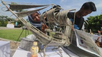 Perserta merangkai hiasan rumah berbentuk sepeda berbahan baku kantong plastik bekas saat lomba daur ulang sampah di Taman Totok Kerot, Kediri, Jawa Timur, Kamis (9/6/2022).  ANTARA FOTO/Prasetia Fauzani
