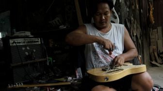 Pekerja menyelesaikan pembuatan gitar di sentra produksi dan reparasi gitar Pak Manto di Jalan Langgar II, Pejaten Timur, Pasar Minggu, Jakarta, Kamis (9/6/2022). [Suara.com/Angga Budhiyanto]