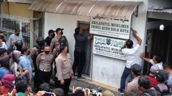 Polisi menurunkan papan bertulis Khilafatul Muslimin dari rumah warga sekaligus kantor cabang kelompok tersebut di Solo, Jawa Tengah, Kamis (9/6/2022). ANTARAFOTO/Maulana Surya
