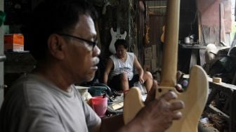 Pekerja menyelesaikan pembuatan gitar di sentra produksi dan reparasi gitar Pak Manto di Jalan Langgar II, Pejaten Timur, Pasar Minggu, Jakarta, Kamis (9/6/2022). [Suara.com/Angga Budhiyanto]