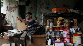 Pekerja menyelesaikan pembuatan gitar di sentra produksi dan reparasi gitar Pak Manto di Jalan Langgar II, Pejaten Timur, Pasar Minggu, Jakarta, Kamis (9/6/2022). [Suara.com/Angga Budhiyanto]