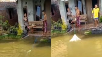 Banjir di Depan Rumah, Pria Ini Malah Asyik Jaring Ikan