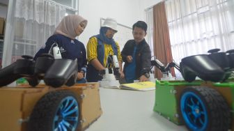 Guru menunjukkan kemampuan robot menulis secara otomatis, saat sosialisasi di SMK Pembangunan Teknologi Robotik UNP di Padang, Sumatera Barat, Sabtu (11/6/2022). [ANTARA FOTO/Iggoy el Fitra/foc]