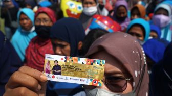 Warga menunjukan kupon paket sembako saat penyaluran paket sembako BUMN di Lapangan Paseban, Bantul, D.I Yogyakarta, Sabtu (11/6/2022). [ANTARA FOTO/Andreas Fitri Atmoko/foc]